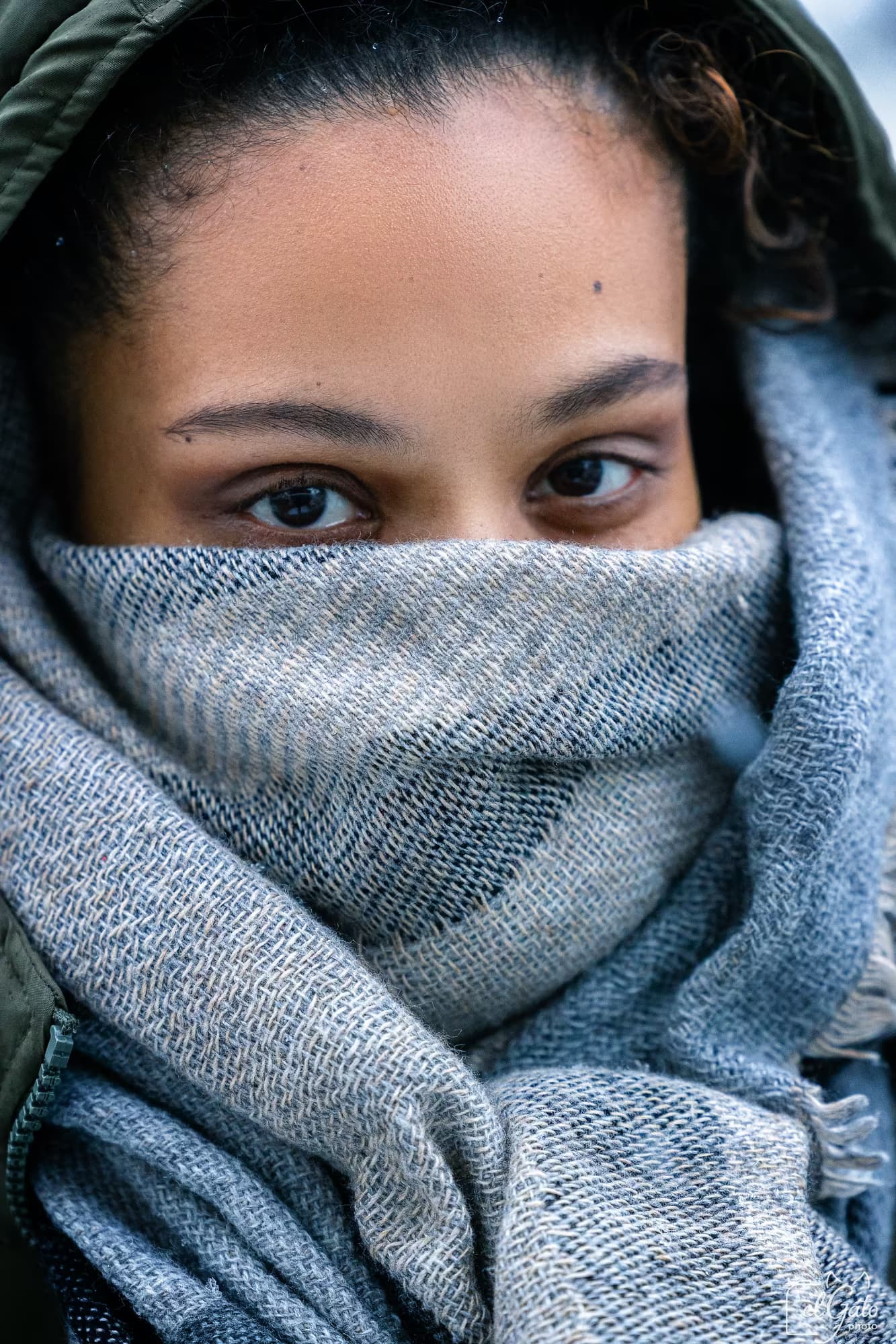 Portrait hivernal — regard au-dessus d’une écharpe grise