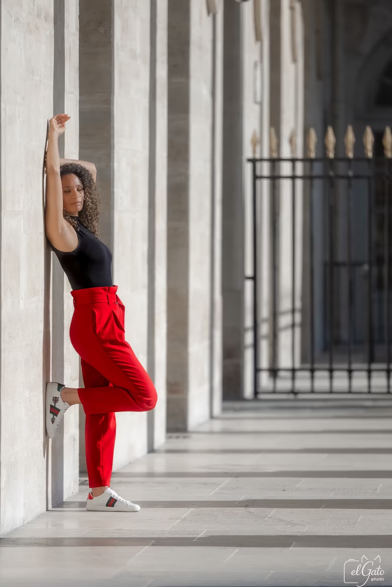 Danseuse en pantalon rouge sous une colonnade en pierre